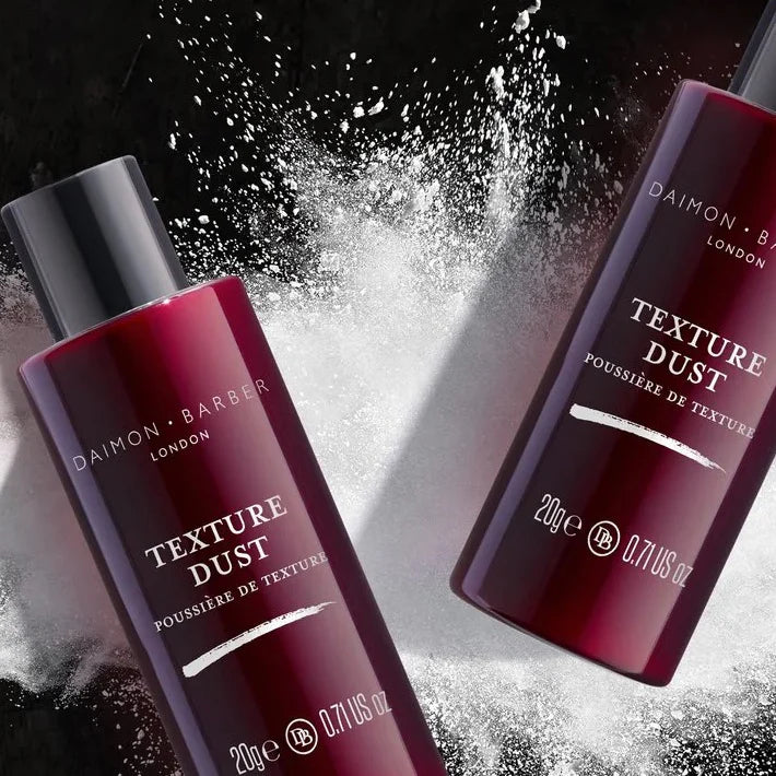 Two bottles of Texture Dust on top of white powder on a black background