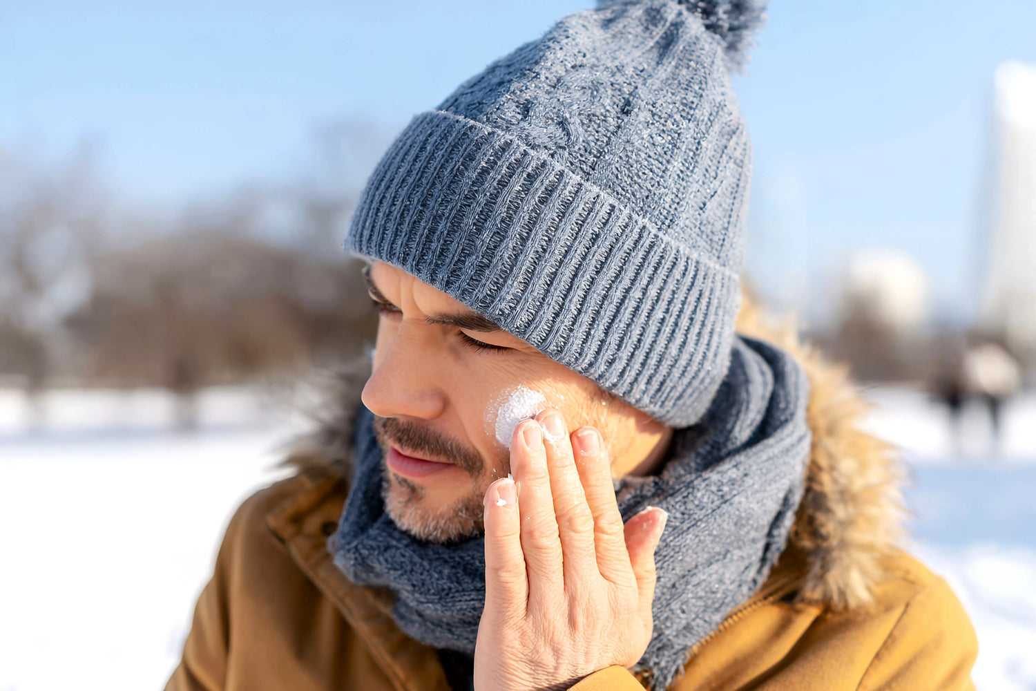 Man applying moisturiser outdoors in winter clothing