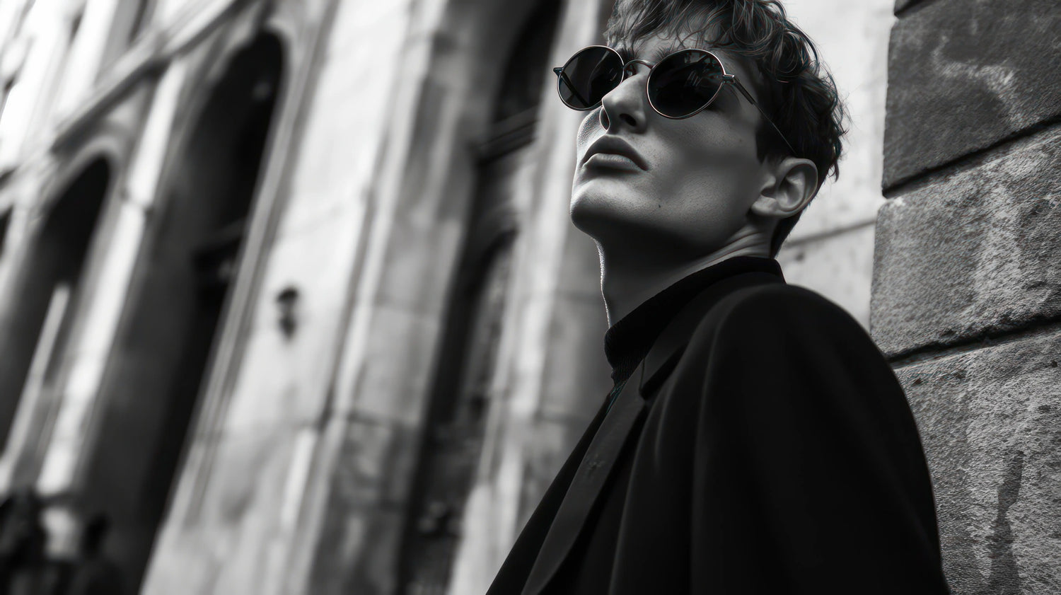 Black and white image of man with round lens sunglasses and mod cut