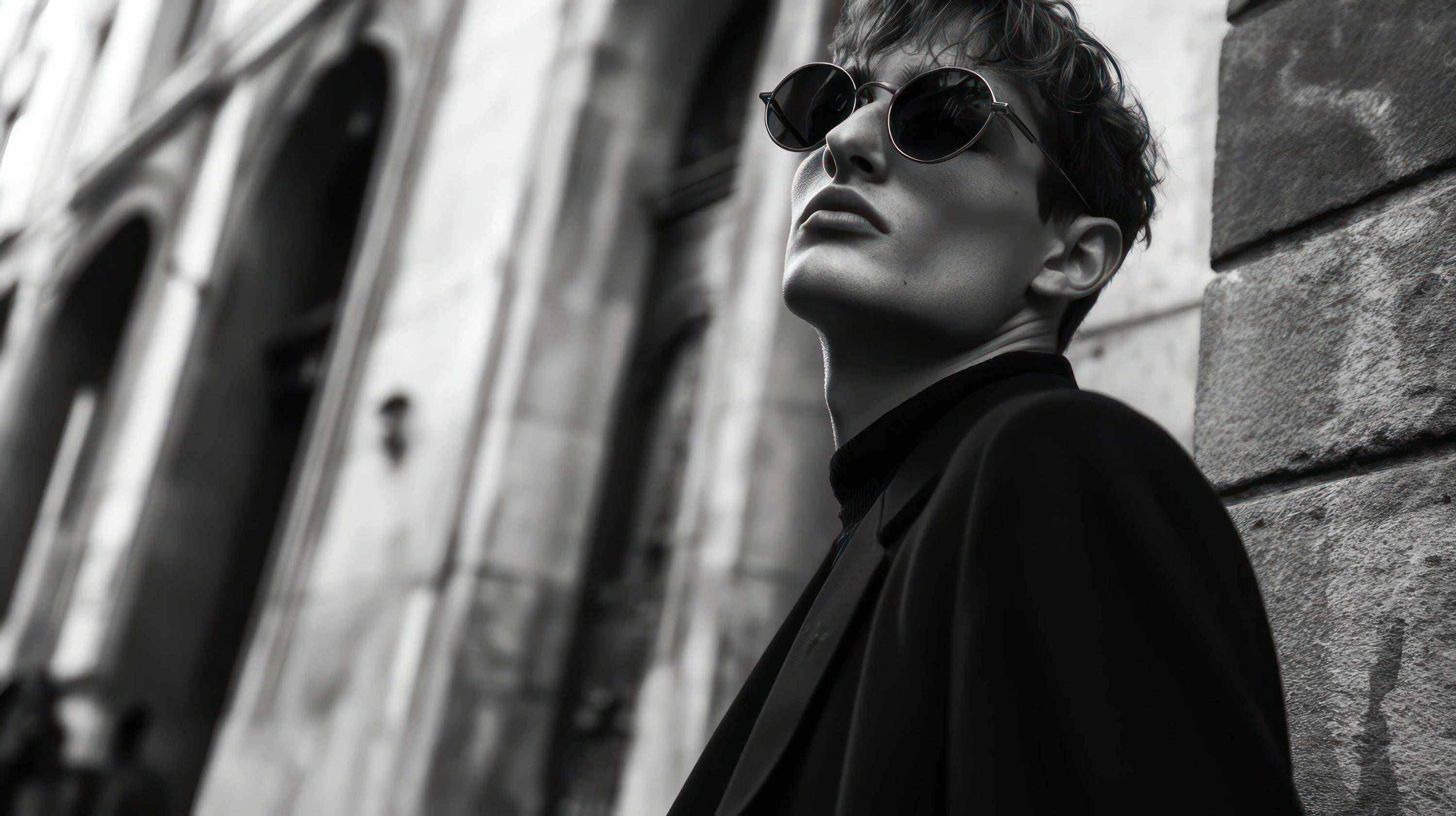 Black and white image of man with round lens sunglasses and mod cut