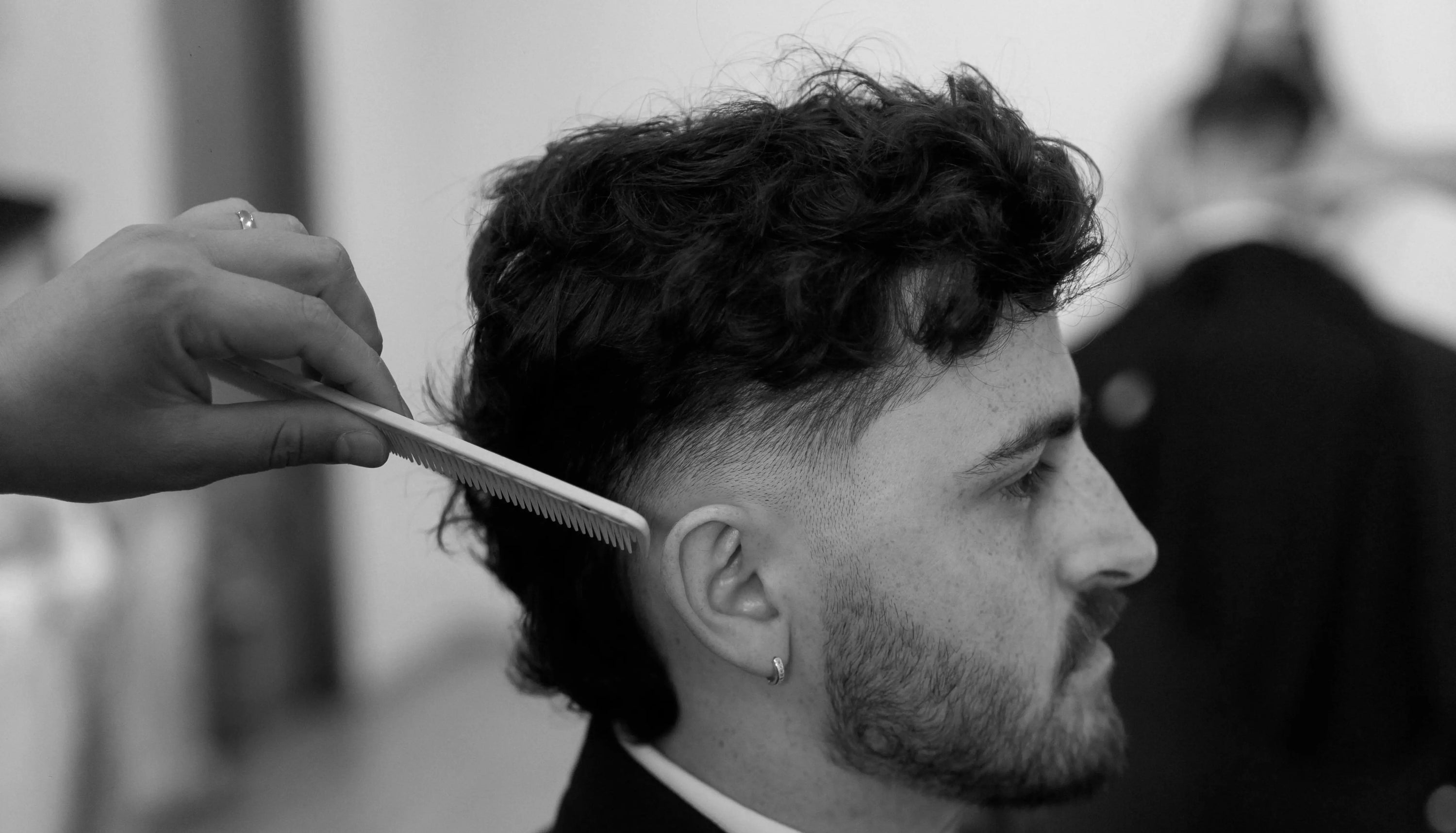 Man getting modern mullet fade haircut at barbers in black and white