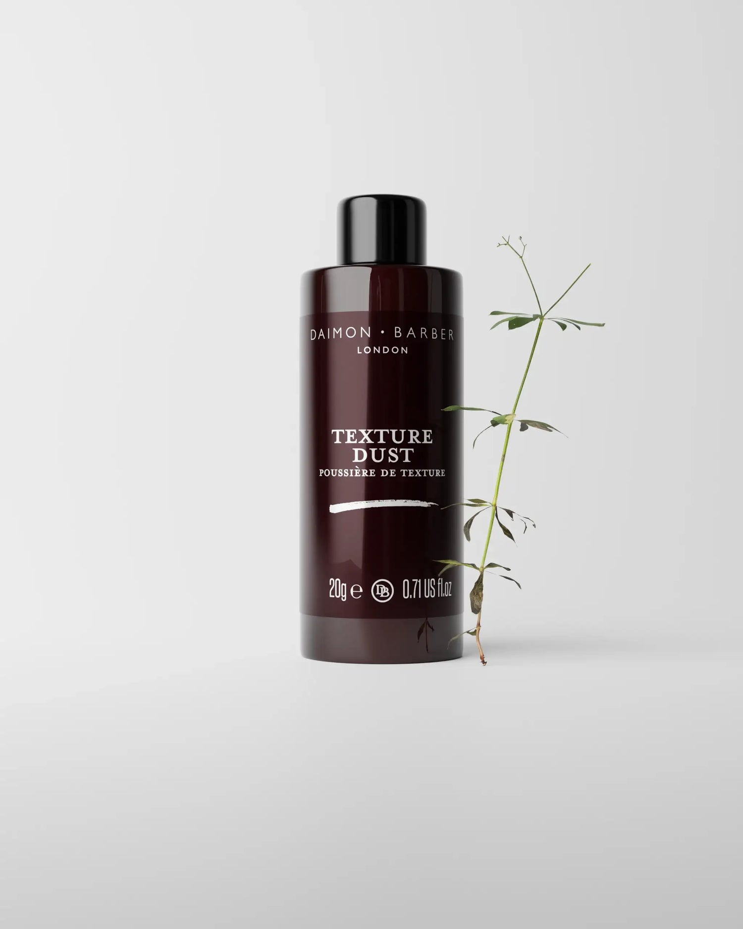 Bottle of Daimon Barber Texture Dust on grey background with small plant