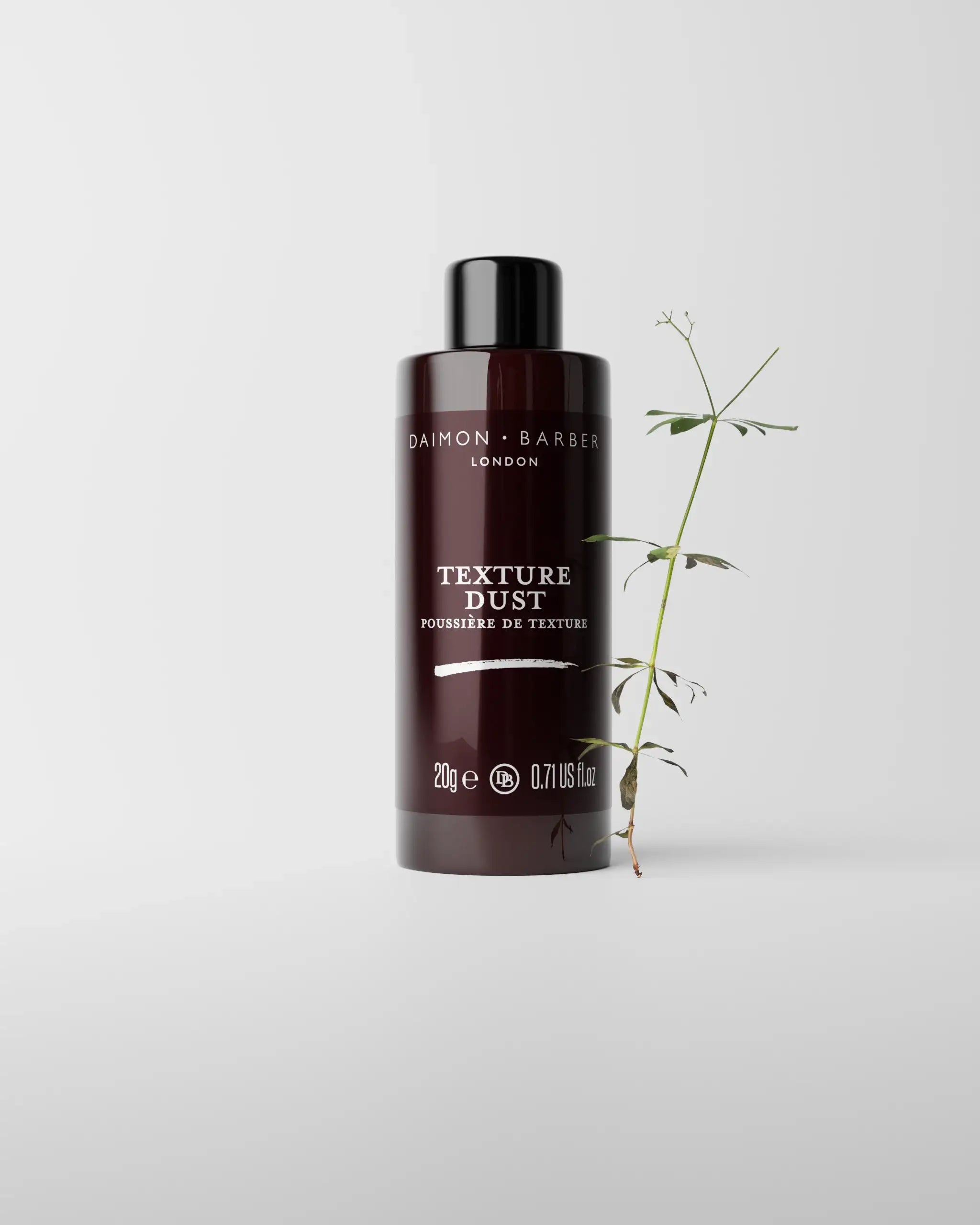 Bottle of Daimon Barber Texture Dust on grey background with small plant