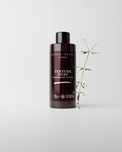 Bottle of Daimon Barber Texture Dust on grey background with small plant