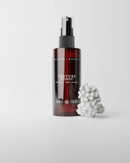 Texture Tonic bottle on grey background with piece of coral