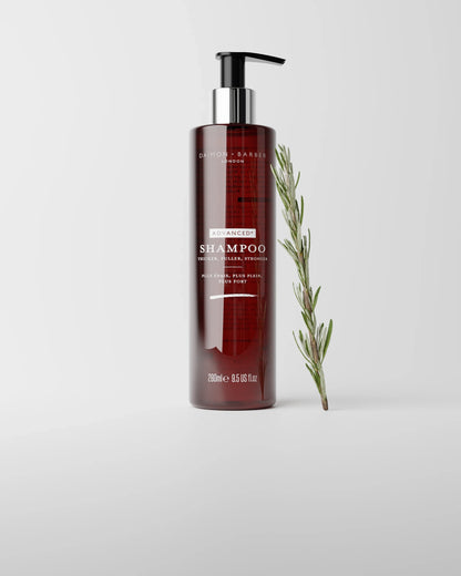 Bottle of Advanced+ Shampoo with a rosemary branch on a light gray background