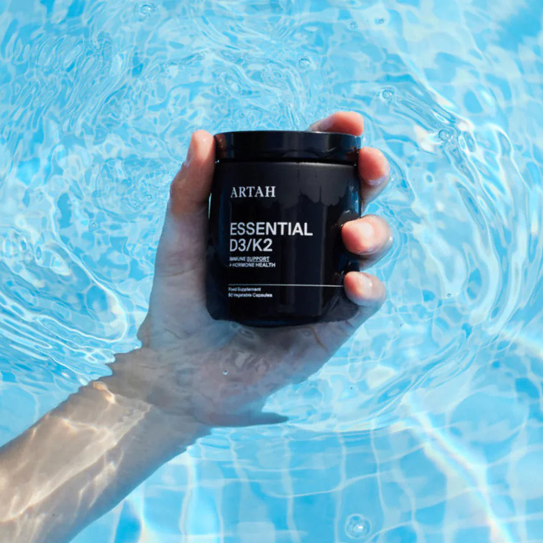 Hand holding a black container labeled &